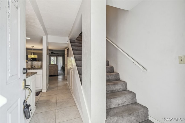 stairs featuring ceiling fan, tile patterned flooring, and sink