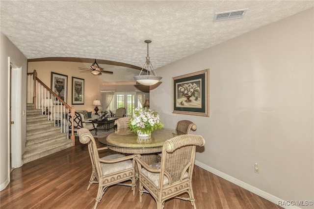 dining area with a textured ceiling, ceiling fan, and dark wood-type flooring