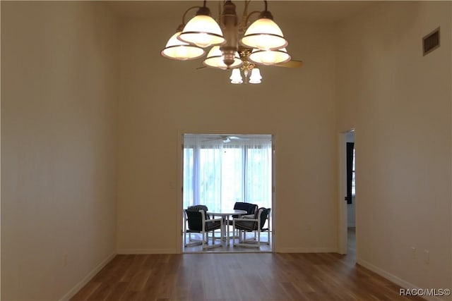 interior space featuring hardwood / wood-style flooring, a towering ceiling, and a notable chandelier