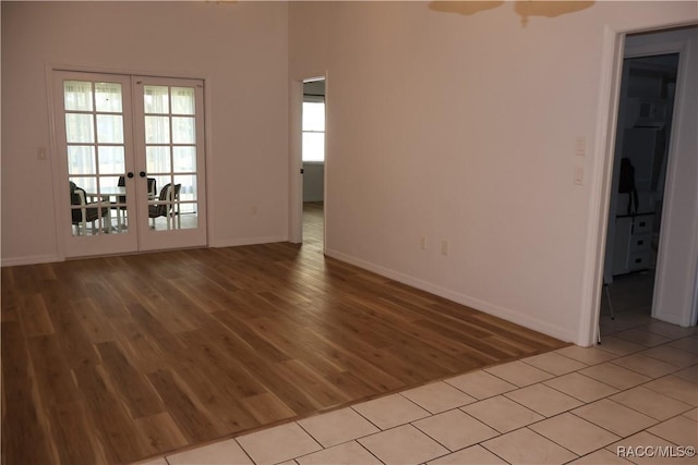 empty room with french doors, light wood-type flooring, and a healthy amount of sunlight