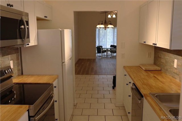 kitchen with wood counters, white cabinets, pendant lighting, and appliances with stainless steel finishes