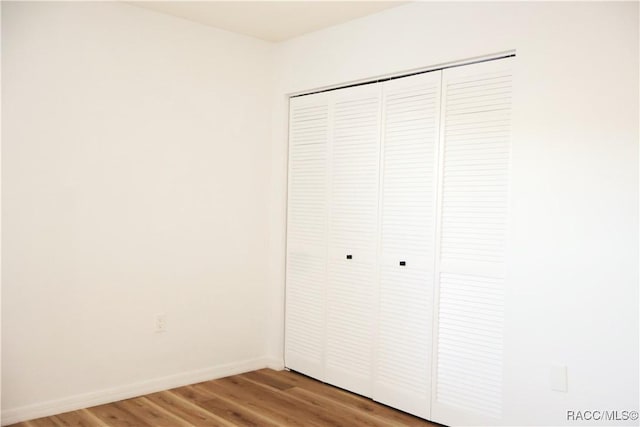 unfurnished bedroom with wood-type flooring and a closet