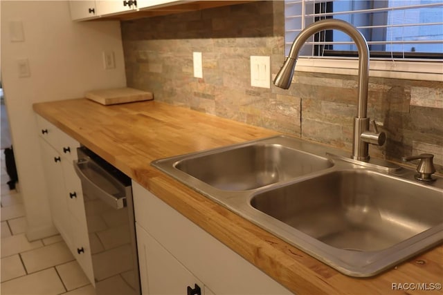 kitchen with tasteful backsplash, sink, white cabinets, and stainless steel dishwasher