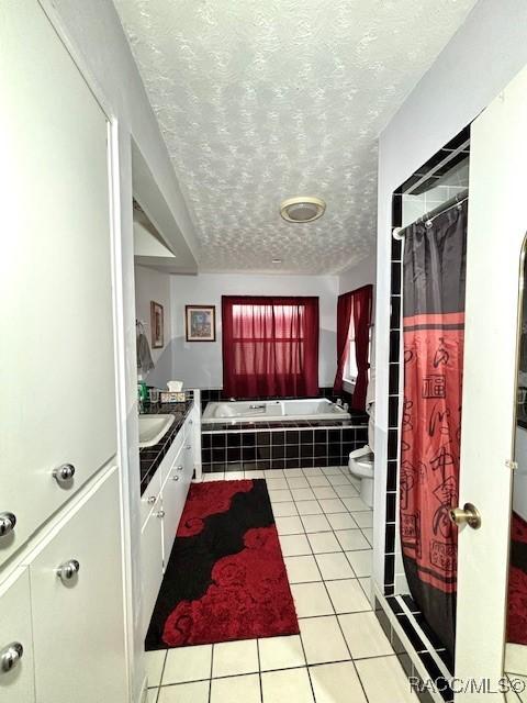 bathroom with a textured ceiling, tiled tub, tile patterned flooring, toilet, and a shower with shower curtain