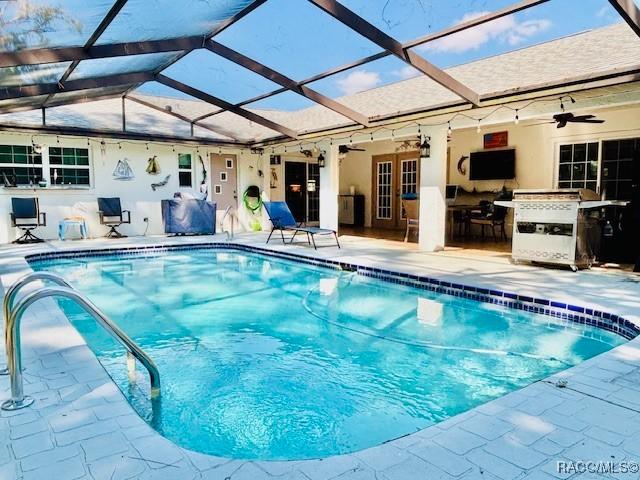 outdoor pool featuring french doors, a ceiling fan, area for grilling, a patio area, and a lanai