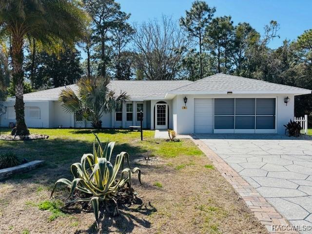 single story home with driveway, a front lawn, an attached garage, and stucco siding