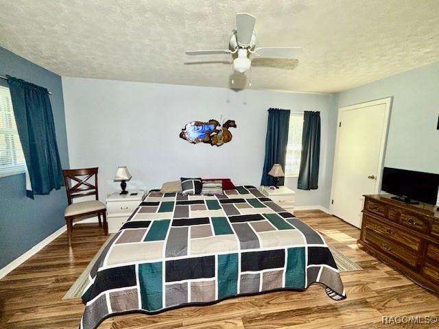 bedroom featuring a textured ceiling, wood finished floors, ceiling fan, and baseboards