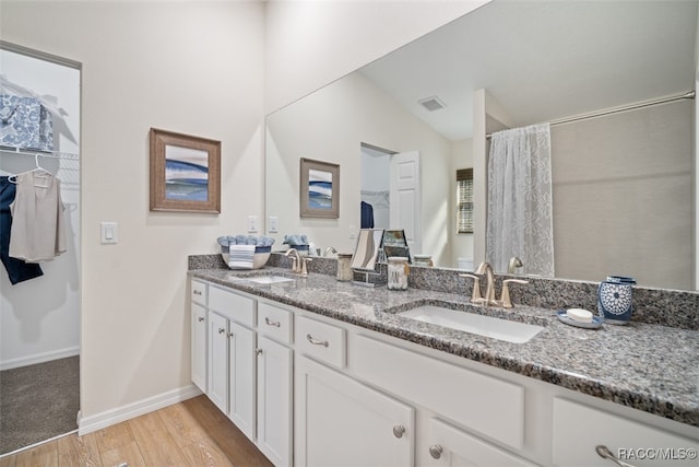 bathroom with vanity, wood-type flooring, vaulted ceiling, and walk in shower