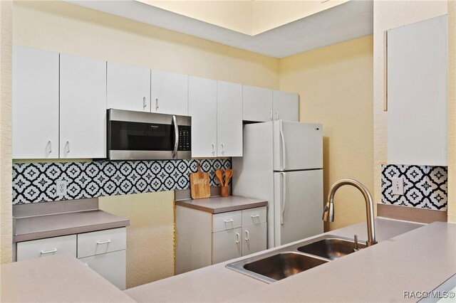 17108 Carrington Park Dr Unit 711, Tampa, FL 33647 - kitchen with white cabinets, a sink, freestanding refrigerator, stainless steel microwave, and backsplash