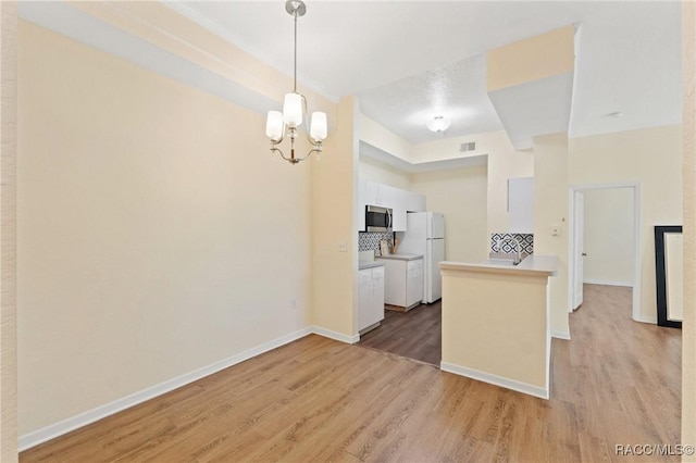 17108 Carrington Park Dr Unit 711, Tampa, FL 33647 - kitchen with light wood-style floors, freestanding refrigerator, white cabinets, stainless steel microwave, and a notable chandelier