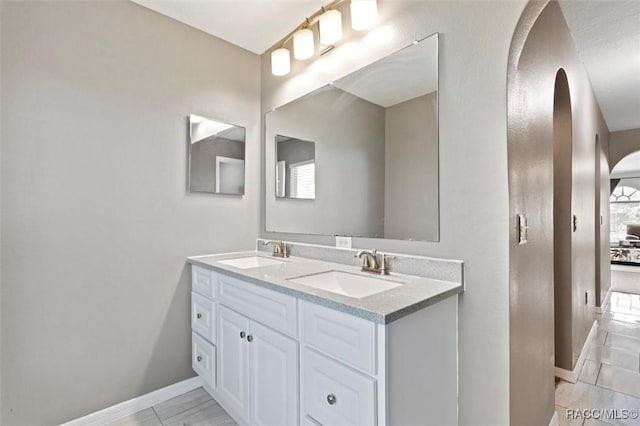bathroom featuring double vanity, baseboards, and a sink