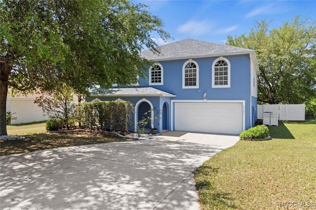 traditional-style home with stucco siding, fence, driveway, a front yard, and an attached garage