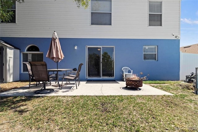 back of property featuring a yard, stucco siding, a fire pit, and a patio area