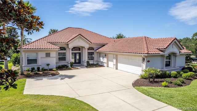 mediterranean / spanish home featuring a garage and a front lawn