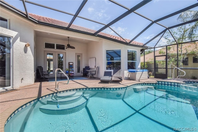 view of swimming pool with glass enclosure, ceiling fan, french doors, and a patio