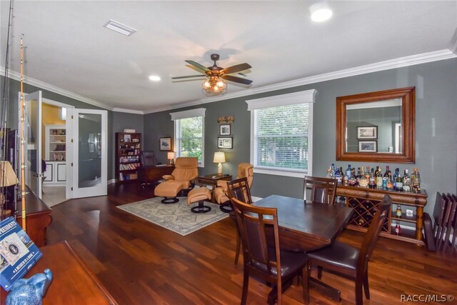 dining area featuring ceiling fan, dark hardwood / wood-style flooring, crown molding, and indoor bar