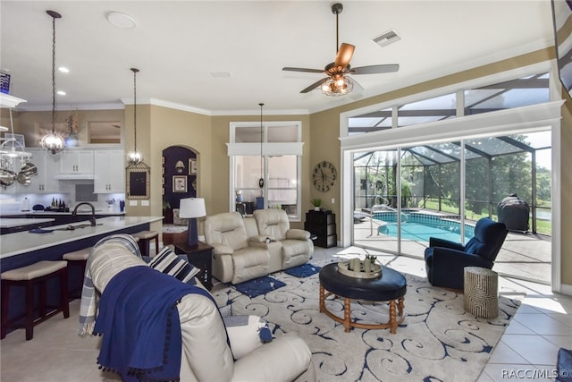 living room featuring light tile patterned floors, ceiling fan, ornamental molding, and sink