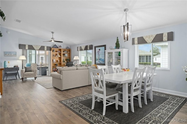 dining room with visible vents, lofted ceiling, wood finished floors, and ceiling fan with notable chandelier