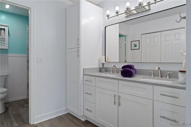 full bathroom with a sink, wainscoting, toilet, and wood finished floors