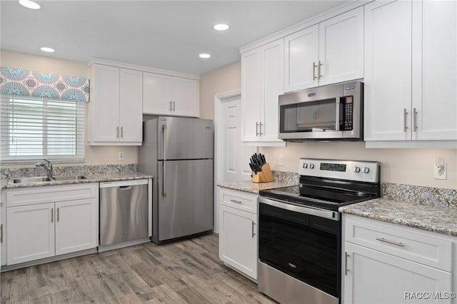 kitchen with a sink, light wood-style flooring, stainless steel appliances, recessed lighting, and white cabinetry