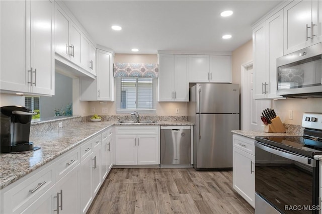 13618 SW 111th Cir, Dunnellon, FL 34432 - kitchen with appliances with stainless steel finishes, white cabinets, a sink, light wood-style floors, and light stone countertops