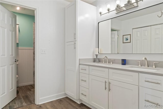 13618 SW 111th Cir, Dunnellon, FL 34432 - bathroom with double vanity, toilet, wood finished floors, a wainscoted wall, and baseboards