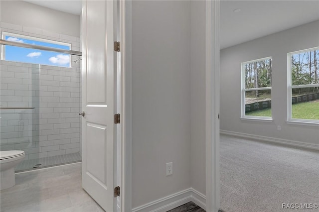 full bath featuring baseboards, toilet, and tiled shower