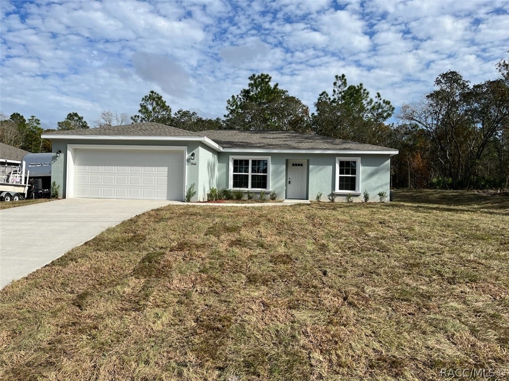 ranch-style house featuring a garage and a front lawn