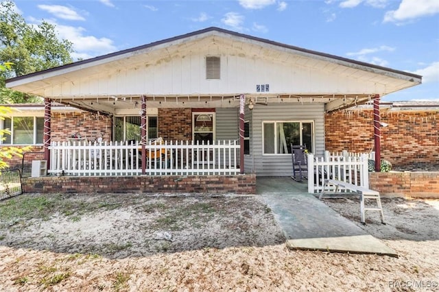 view of front facade featuring fence, brick siding, and a patio