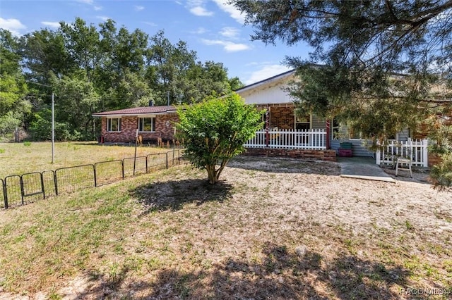 view of front of property featuring brick siding, a front lawn, fence, and covered porch