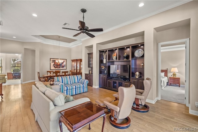 living room featuring ceiling fan with notable chandelier, light wood-type flooring, and crown molding