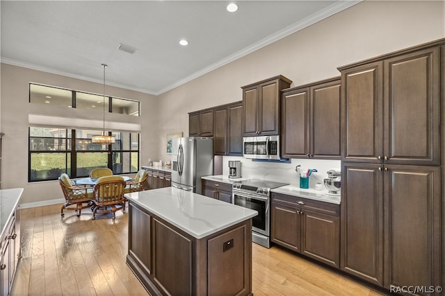 kitchen with light hardwood / wood-style floors, dark brown cabinets, pendant lighting, and appliances with stainless steel finishes