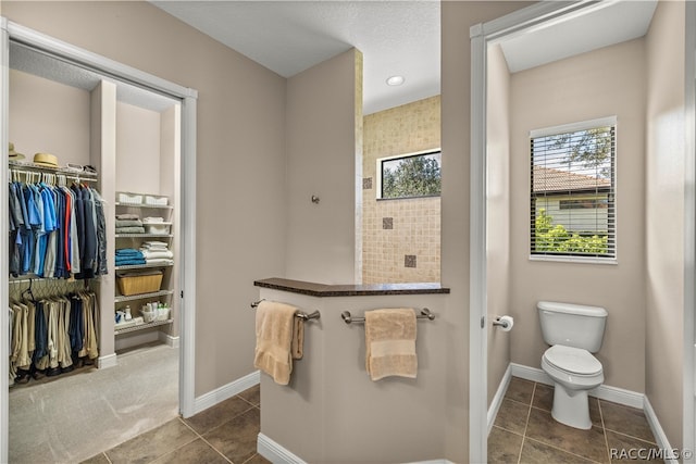 bathroom with toilet, tile patterned floors, and walk in shower