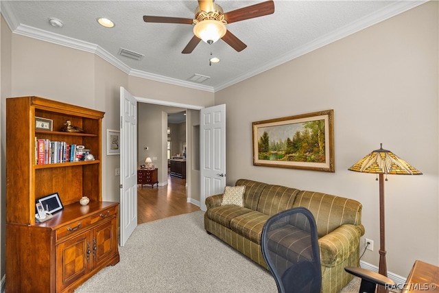 living room featuring light carpet, a textured ceiling, ceiling fan, and ornamental molding