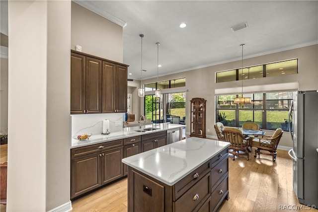 kitchen with pendant lighting, a center island, appliances with stainless steel finishes, and sink