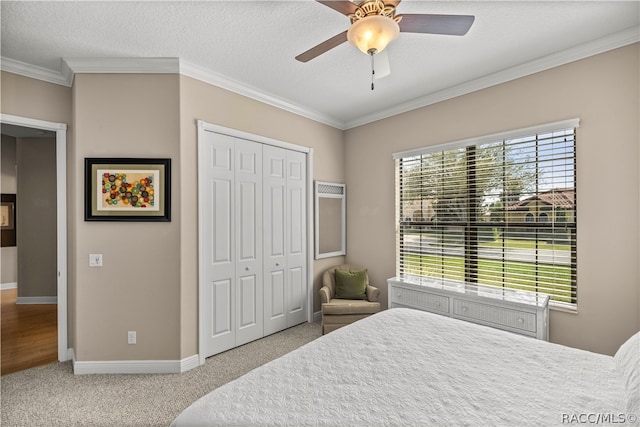 carpeted bedroom with a textured ceiling, a closet, ceiling fan, and ornamental molding