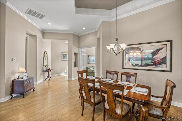 dining space with an inviting chandelier, ornamental molding, and light hardwood / wood-style flooring