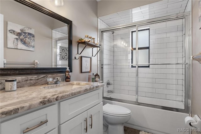 full bathroom with vanity, shower / bath combination with glass door, and toilet