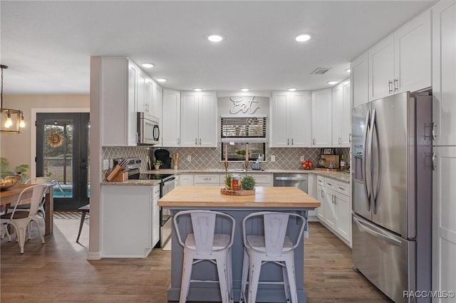 kitchen featuring white cabinetry, stainless steel appliances, a kitchen bar, and pendant lighting