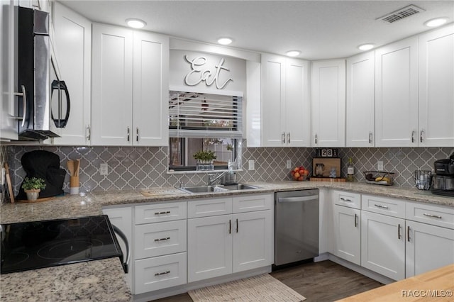 kitchen with stainless steel appliances, white cabinetry, sink, and decorative backsplash