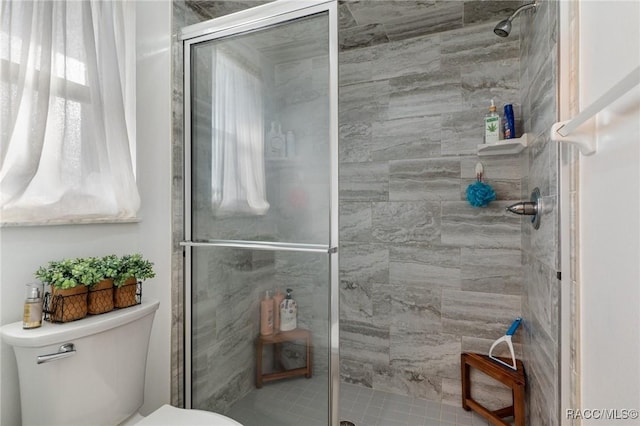 bathroom with a shower with shower door and toilet