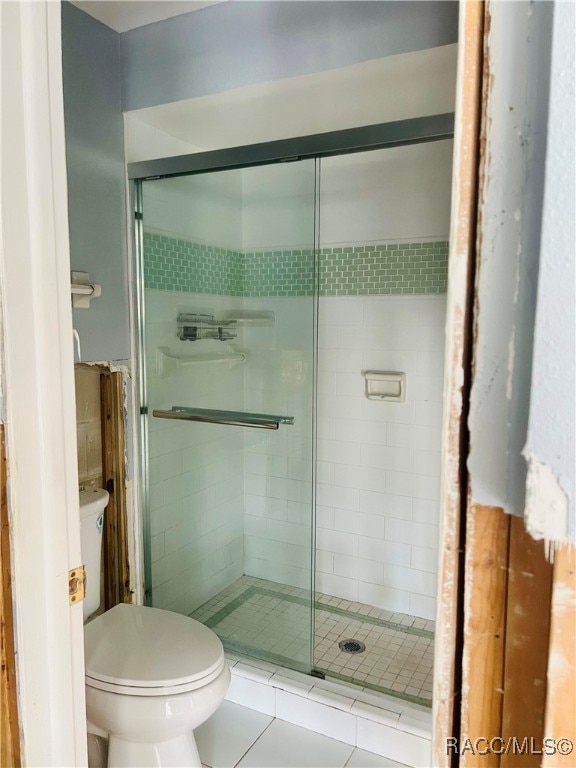 bathroom featuring tile patterned flooring, toilet, and walk in shower