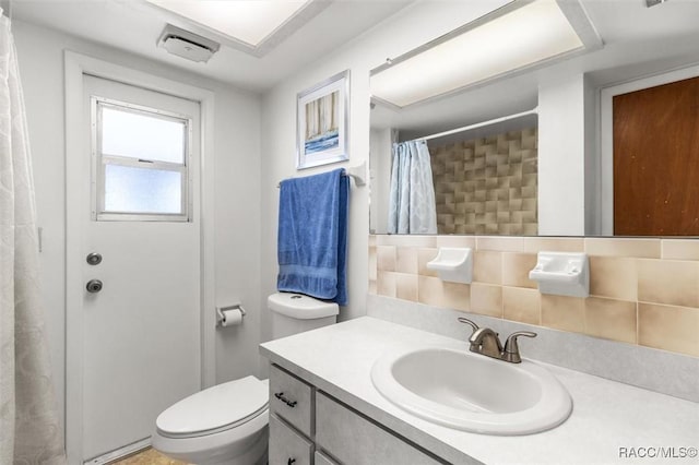 bathroom with tasteful backsplash, vanity, toilet, and curtained shower