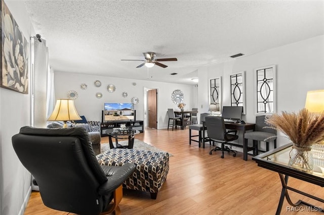 living room featuring a textured ceiling, ceiling fan, and light hardwood / wood-style floors