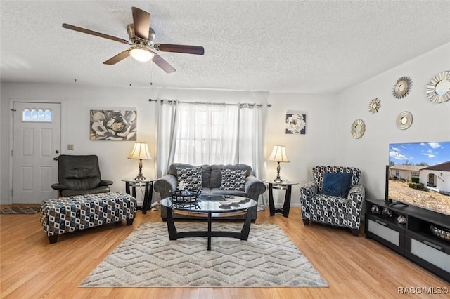 living room featuring ceiling fan, a textured ceiling, and light hardwood / wood-style floors