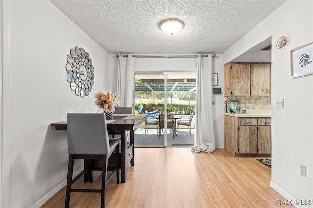 dining room featuring light wood-type flooring and a textured ceiling