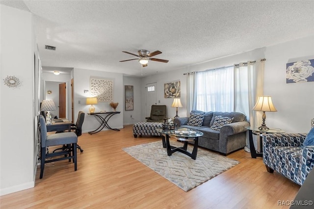 living room with ceiling fan, a textured ceiling, and light hardwood / wood-style flooring