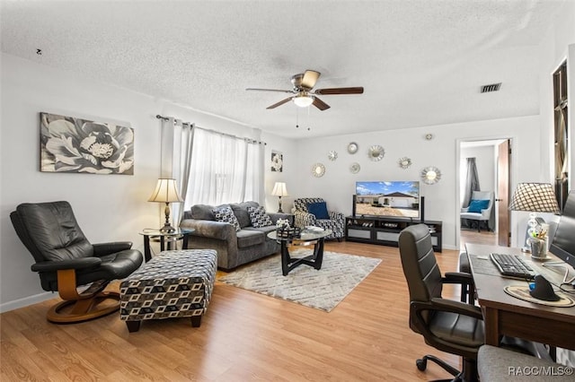 living room featuring ceiling fan, wood-type flooring, and a textured ceiling