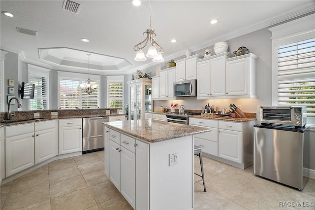 kitchen with crown molding, an inviting chandelier, a sink, stainless steel appliances, and visible vents