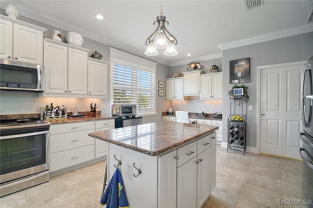 kitchen with a kitchen island, visible vents, appliances with stainless steel finishes, light tile patterned floors, and white cabinets